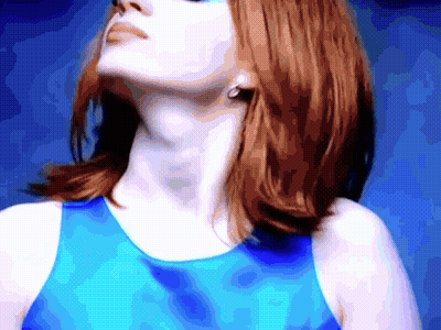 A Woman With Red Hair Is Wearing A Blue Tank Top And Earrings GIF