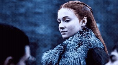 A Woman With Red Hair Is Wearing A Fur Coat And Looking At The Camera . GIF