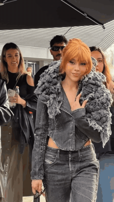 A Woman With Red Hair Is Wearing A Grey Jacket GIF