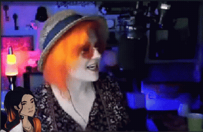 A Woman With Red Hair Is Wearing A Hat And Sunglasses While Talking To Another Woman . GIF