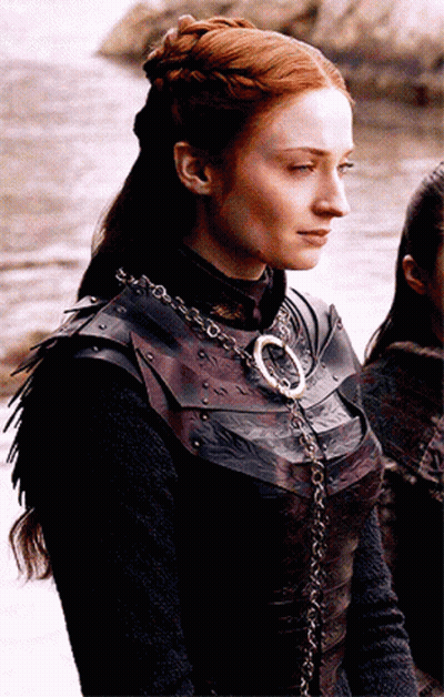 A Woman With Red Hair Is Wearing A Leather Armor And A Necklace With The Letter O On It GIF