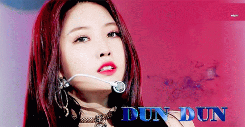 A Woman With Red Hair Is Wearing A Microphone And The Name Dun Dun Is Visible In Blue GIF