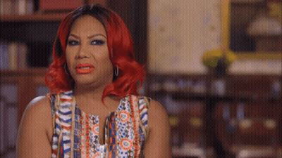 A Woman With Red Hair Is Wearing A Multicolored Top GIF