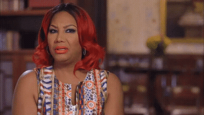 A Woman With Red Hair Is Wearing A Multicolored Top GIF