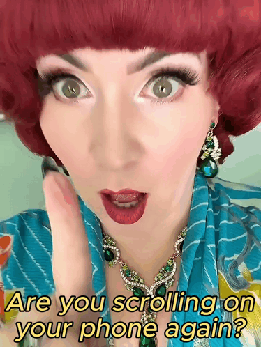 A Woman With Red Hair Is Wearing A Necklace And Earrings And Says Are You Scrolling On Your Phone Again GIF