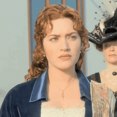 A Woman With Red Hair Is Wearing A Necklace That Has A Key On It GIF