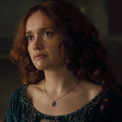 A Woman With Red Hair Is Wearing A Necklace With A Leaf Pendant GIF