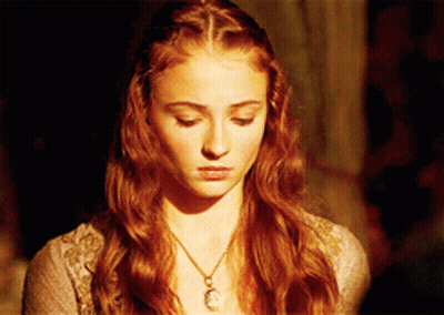 A Woman With Red Hair Is Wearing A Necklace With A Pendant On It GIF
