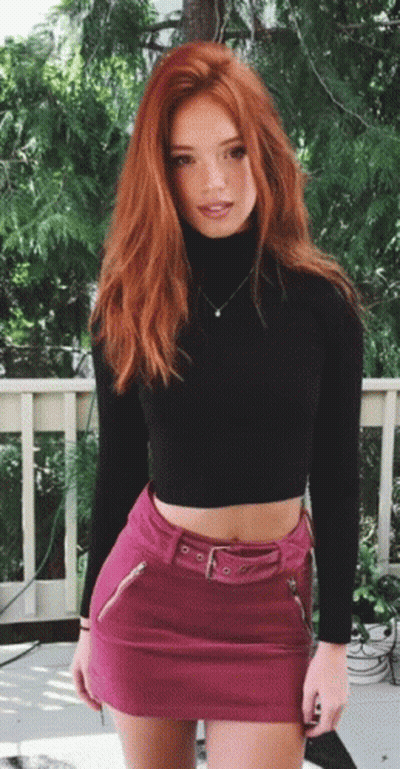 A Woman With Red Hair Is Wearing A Pink Skirt And A Black Turtleneck GIF