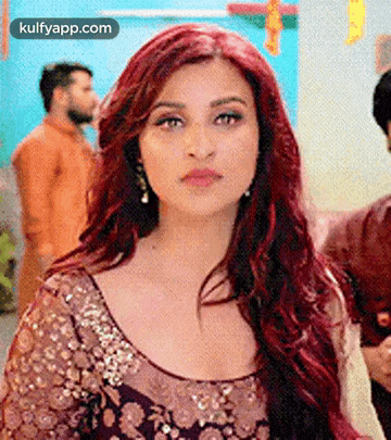 A Woman With Red Hair Is Wearing A Purple And Gold Dress And Earrings . GIF