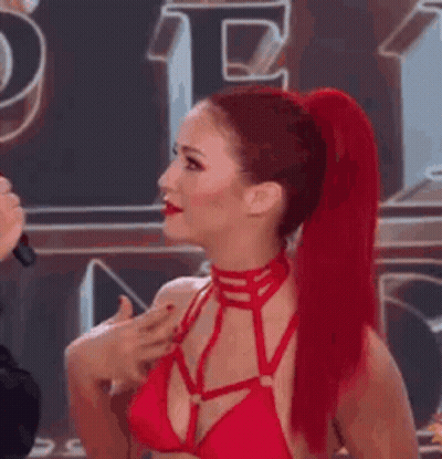 A Woman With Red Hair Is Wearing A Red Bikini Top And A Red Choker . GIF