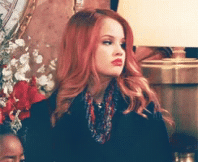 A Woman With Red Hair Is Wearing A Scarf And A Black Jacket GIF
