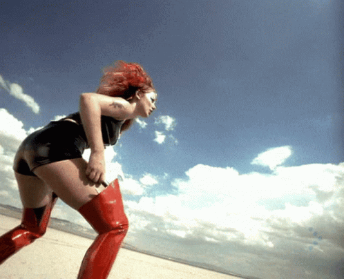 A Woman With Red Hair Is Wearing Red Boots GIF