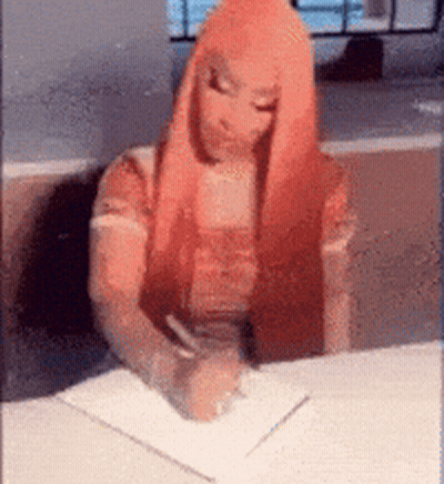 A Woman With Red Hair Is Writing On A Piece Of Paper . GIF