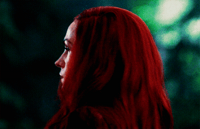 A Woman With Red Hair Looks At The Camera With A Green Background GIF