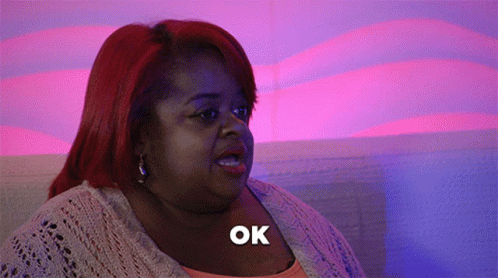 A Woman With Red Hair Says Ok In A Purple Background GIF