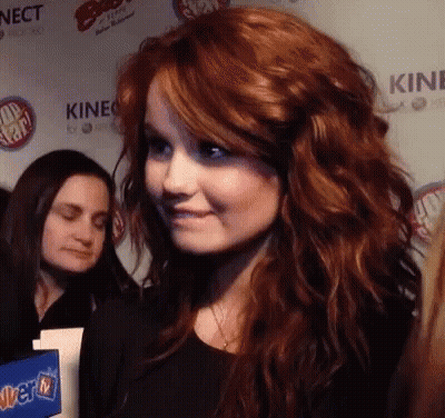 A Woman With Red Hair Stands In Front Of A Wall That Says Kinect On It GIF