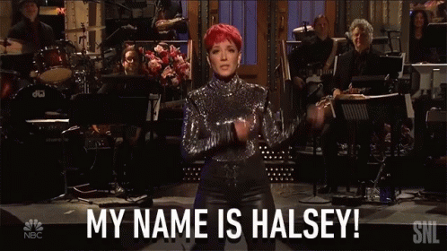 A Woman With Red Hair Stands In Front Of An Orchestra And Says Her Name Is Halsey GIF