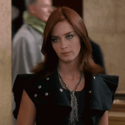 A Woman With Red Hair Wearing A Black Vest GIF