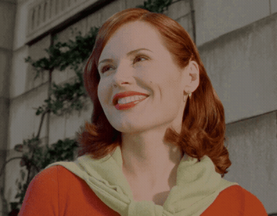A Woman With Red Hair Wearing A Green Sweater Smiles GIF