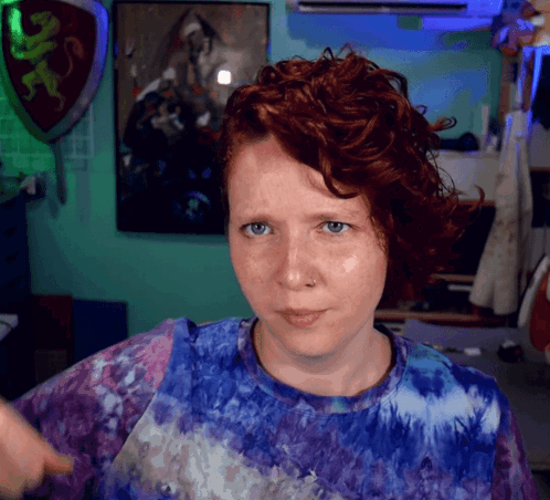 A Woman With Red Hair Wearing A Purple Tie Dye Shirt GIF