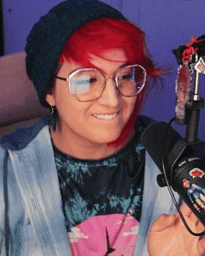 A Woman With Red Hair Wearing Glasses And A Beanie GIF