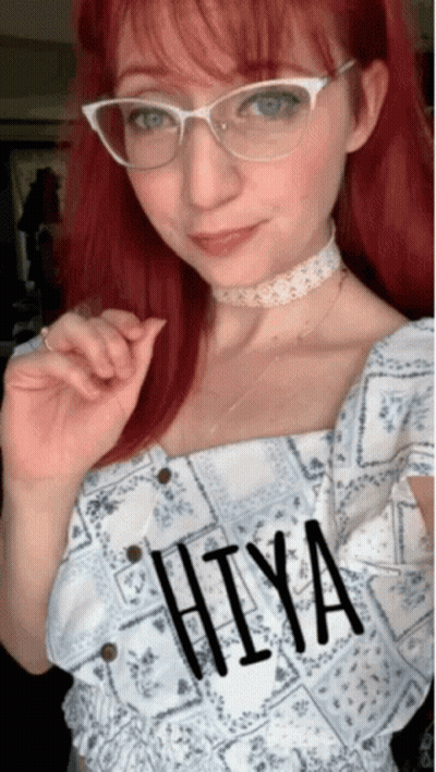A Woman With Red Hair Wearing Glasses And A Choker Has The Word Hiya Written On Her Top GIF