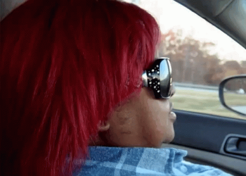 A Woman With Red Hair Wearing Sunglasses And A Plaid Shirt GIF