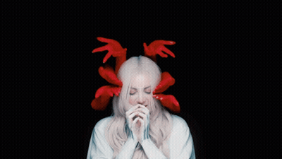A Woman With Red Hands On Her Head And A White Robe GIF
