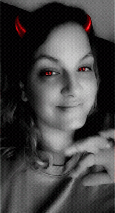 A Woman With Red Horns On Her Head Is Smiling GIF