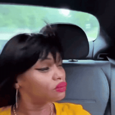 a woman with red lips is sitting in the back seat of a car