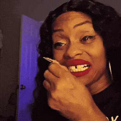A Woman With Red Lipstick And A Black Shirt With The Letter V On It GIF