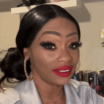 A Woman With Red Lipstick And Gold Hoop Earrings Is Making A Funny Face . GIF