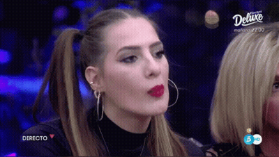 A Woman With Red Lipstick And Hoop Earrings Is On A Television Screen That Says Deluxe GIF