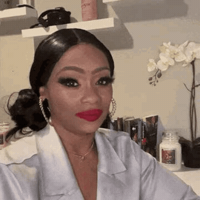 A Woman With Red Lipstick And Hoop Earrings Is Taking A Selfie In A Room . GIF