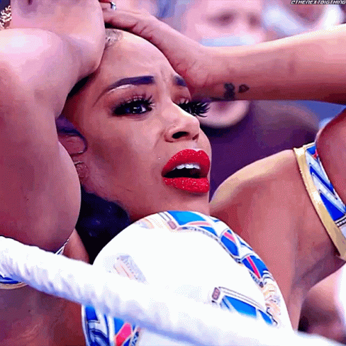 A Woman With Red Lipstick Is Being Held By Another Woman In A Wrestling Ring .. GIF