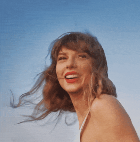 A Woman With Red Lipstick Is Smiling And Her Hair Is Blowing In The Wind GIF