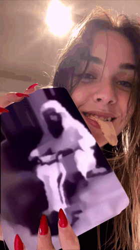 A Woman With Red Nails Is Holding A Card With A Picture Of An Astronaut On It GIF