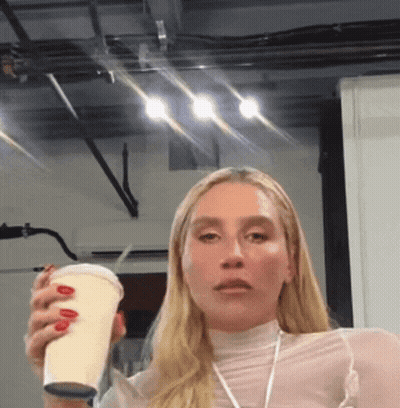 A Woman With Red Nails Is Holding A Cup In Her Right Hand GIF