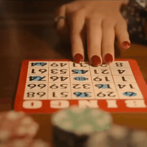 A Woman With Red Nails Is Playing Bingo With A Red Board GIF