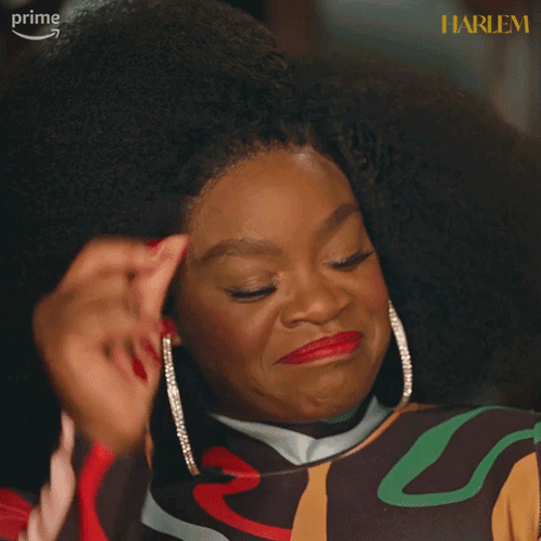A Woman With Red Nails Is Smiling In Front Of A Harlem Sign GIF