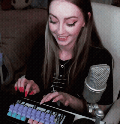 A Woman With Red Nails Is Typing On A Keyboard In Front Of A Silver Microphone GIF
