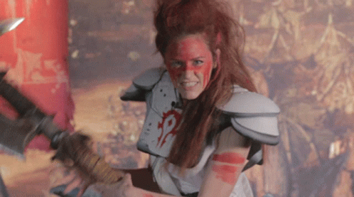 A Woman With Red Paint On Her Face Is Holding A Large Sword GIF