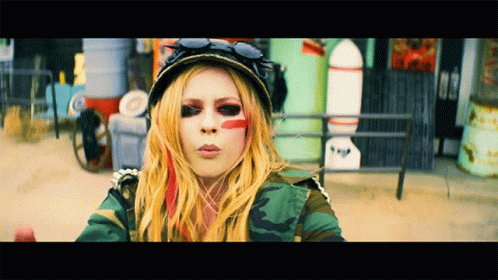 A Woman With Red Paint On Her Face Is Wearing A Camo Jacket GIF