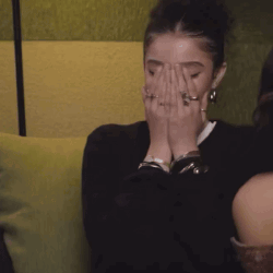 A Woman With Rings On Her Fingers Is Covering Her Face With Her Hands . GIF