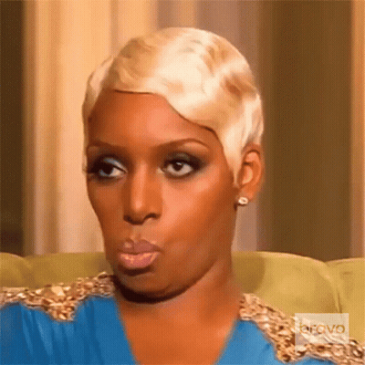 A Woman With Short Blonde Hair Is Sitting On A Couch With Bravo Written On The Bottom Right GIF