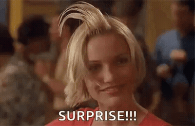 A Woman With Short Blonde Hair Is Smiling And Holding Her Hair Up In The Air . GIF