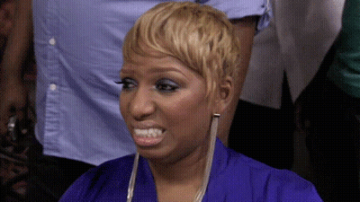 A Woman With Short Blonde Hair Is Wearing A Blue Shirt And Earrings . GIF