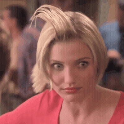 A Woman With Short Blonde Hair Is Wearing A Red Shirt And Looking At The Camera . GIF