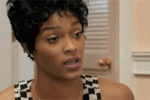 A Woman With Short Curly Hair Is Making A Funny Face In Front Of A Window . GIF